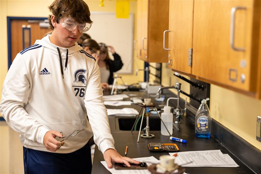 A boy watches a Bunsen burner during an experiment
